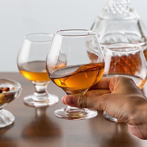 close up of hand swirling brandy in glass