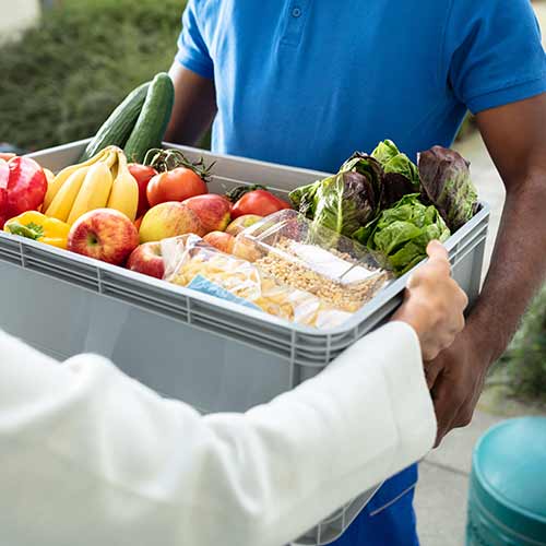 employee delivering basket of groceries to a restaurant