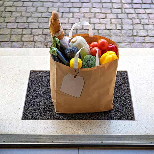 paper bag with groceries delivered and left outside at entrance door