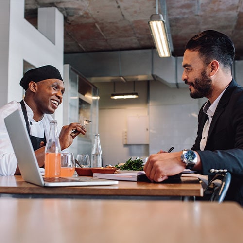 restaurant manager interviews chef at dining table in a well lit room