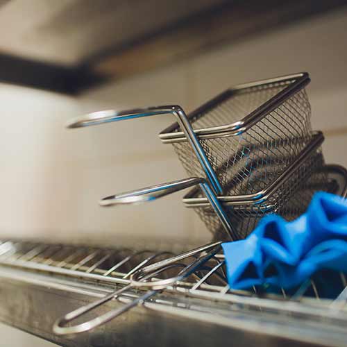 stacked fryer baskets in commercial kitchen