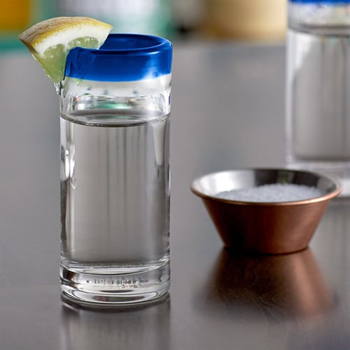 vodka in colored shot glass garnished with slice of lemon