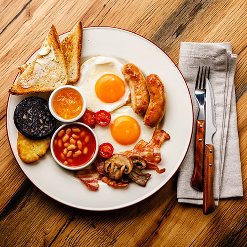 Full fry-up English breakfast with fried eggs, sausages, bacon, black pudding, beans, and toasts