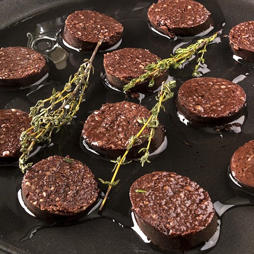 Black pudding and thyme frying in a pan with oil