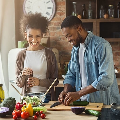 Couple preparing meal in kitchen surrounded by fresh ingredients