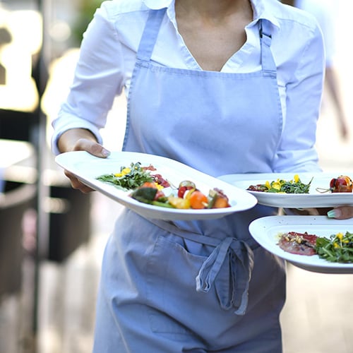 server walking with three plates of food