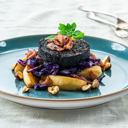 Warm salad of red cabbage black pudding and apple with crispy bacon and crushed hazelnuts