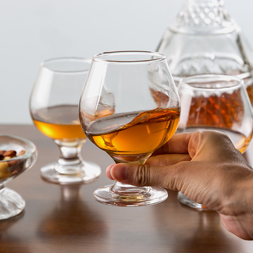 Hand holding a glass of brandy, preparing to drink