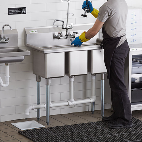 employee washing dishes at a 3 compartment sink