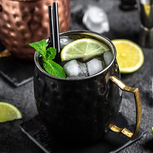 top view of icy cold moscow mules with ginger beer and vodka on black background