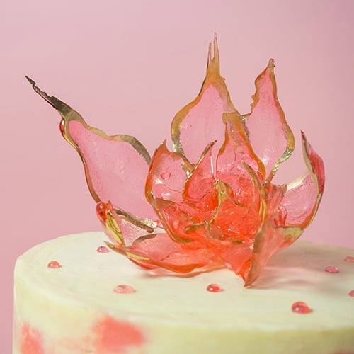 Red isomalt sugar piece flower on top of a cake