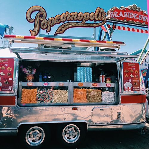 food truck with fair food and custom neon popcornopolis sign