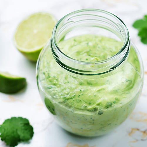 green avocado salsa dressing in a clear pitcher