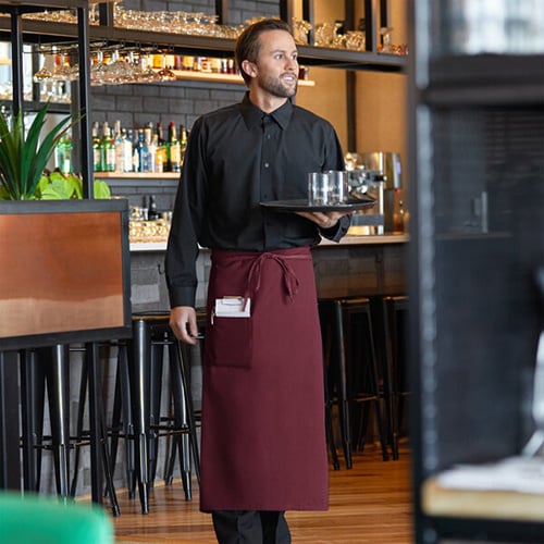 male server at upscale restaurant carrying two drinks on a tray