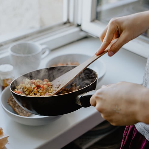 Person Holding a Black Frying Pan with Rice