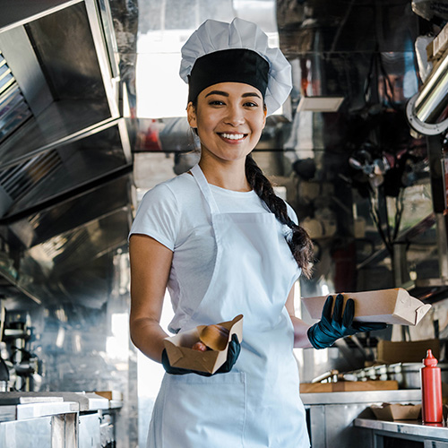 smiling female asian chef holding carton plates in food truck