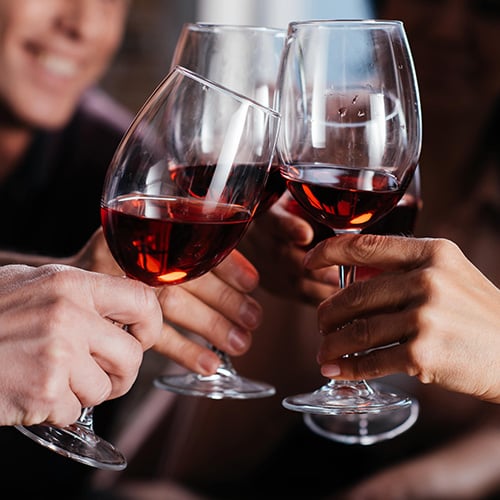 friends drinking red wine clinking glasses together