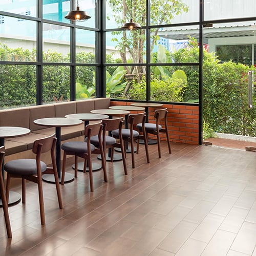 wooden table and chair inside of glass room with garden