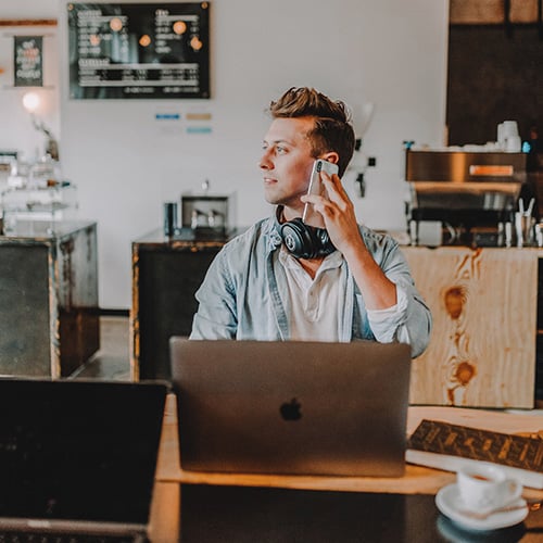 business owner talking on cellphone in front of laptop
