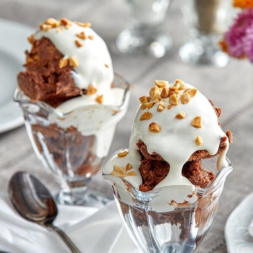 ice cream sundaes with peanuts and whipped cream on top