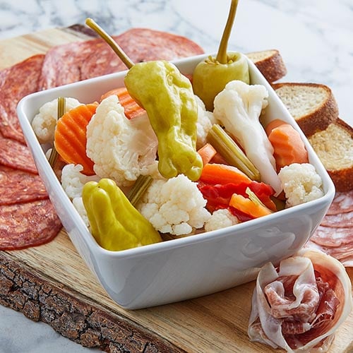 banana peppers cauliflower and carrot medallions in square white ceramic bowl