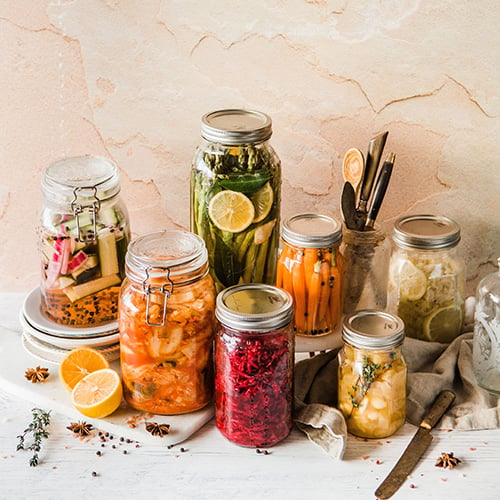 multiple mason jars filled with different colored fermented and pickled vegetables