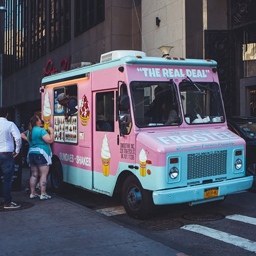 people standing in line waiting to order from a blue and pink ice cream truck