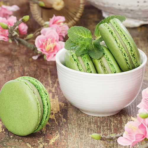 green tea macarons in mini ceramic bowl with pink floral background