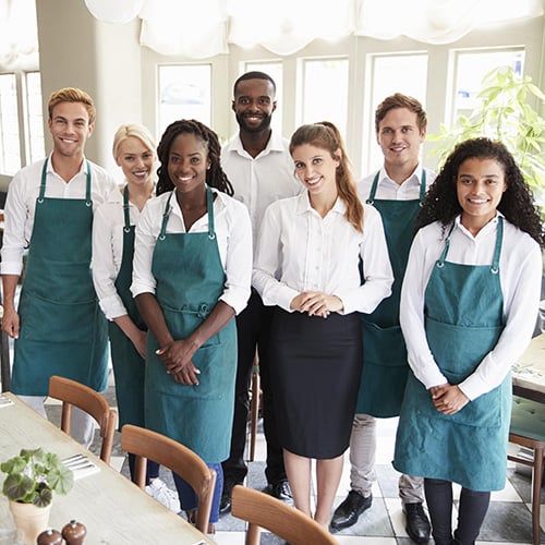 portrait of restaurant team standing in empty dining room