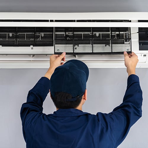 technician serviceman removing air filter out of air conditioner for cleaning