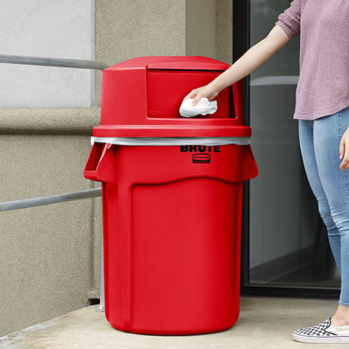 woman throwing away trash in large red trash can