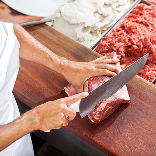 butcher cutting meat at counter