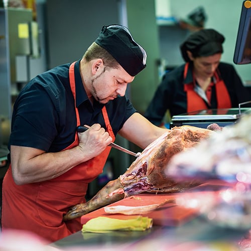 butchers boning a ham in a modern butcher shop