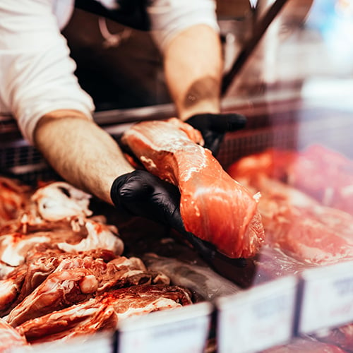 close up on butchers hands in gloves working in butcher shop