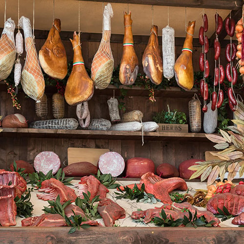 meat assortment and sausages in butcher shop on wooden board