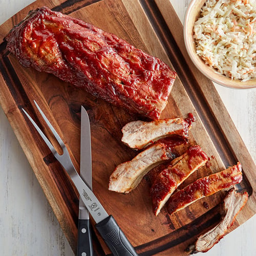 sliced barbecue spare ribs on wooden serving board