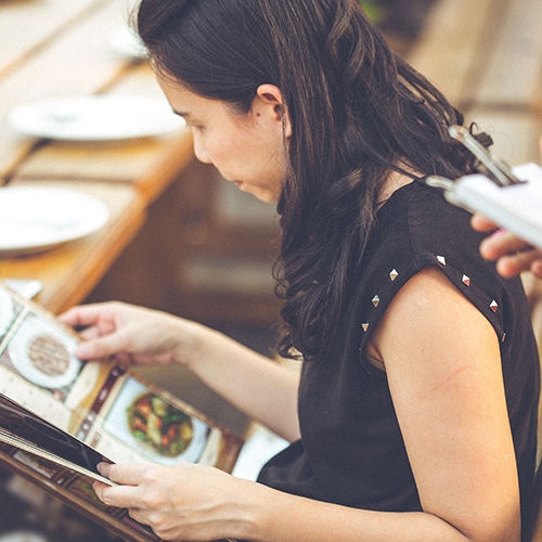 woman looking at menu while waitress waits to take order