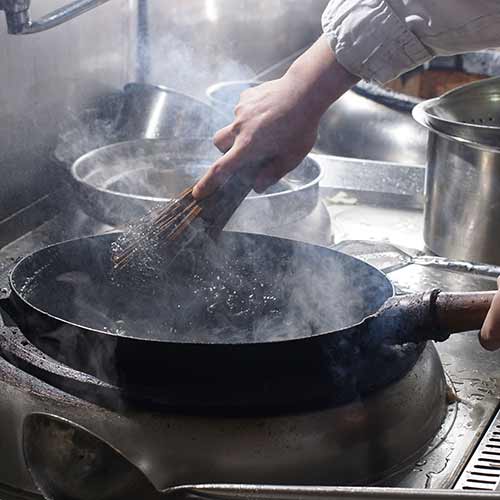 cleaning wok with wooden sticks and metal wire