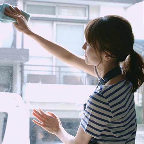 female employee with apron cleaning window