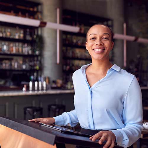 A woman host standing at counter using digital tablet.