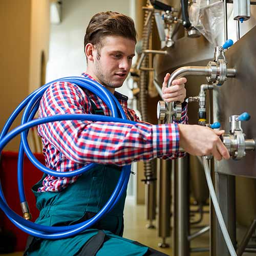 maintenance worker examining brewery machine