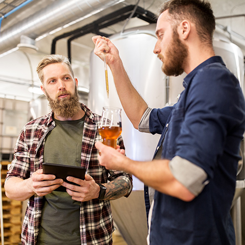 men with pipette testing craft beer at brewery
