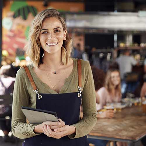 Hostess holding menus serving in busy restaurant.