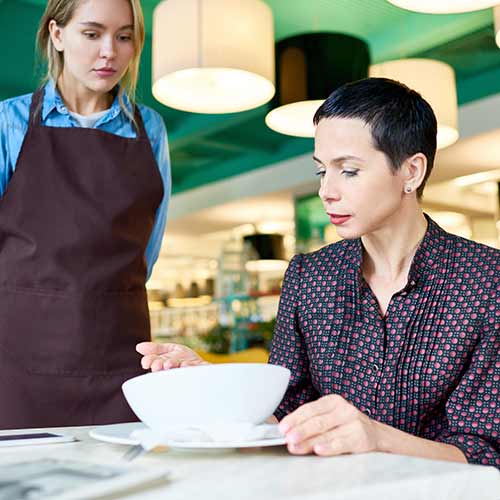 woman complaining about food quality and taste to young waitress in cafe