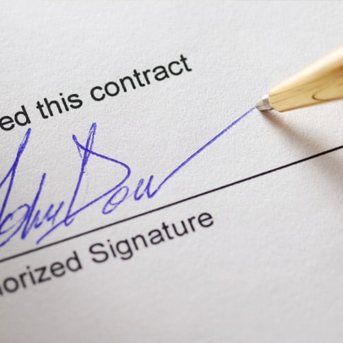 pen signing a signature on a document