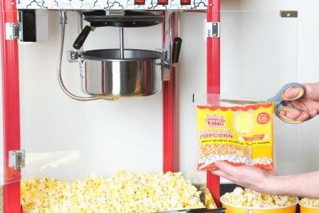 Person cutting open Carnival King popcorn kit in front of popcorn popper