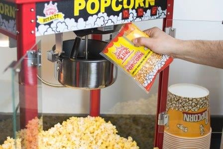 Person pouring Carnival King popcorn kit into popcorn popper