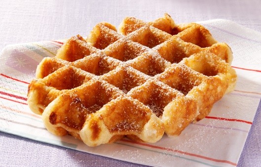 Liege waffle dusted with powdered sugar on white striped napkin