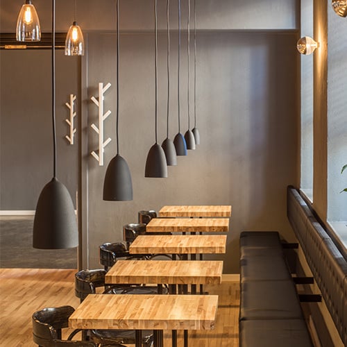 row of wooden tables, chairs, and hanging lights at modern restaurant