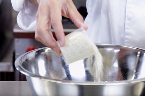 white rice being poured into a metal bowl